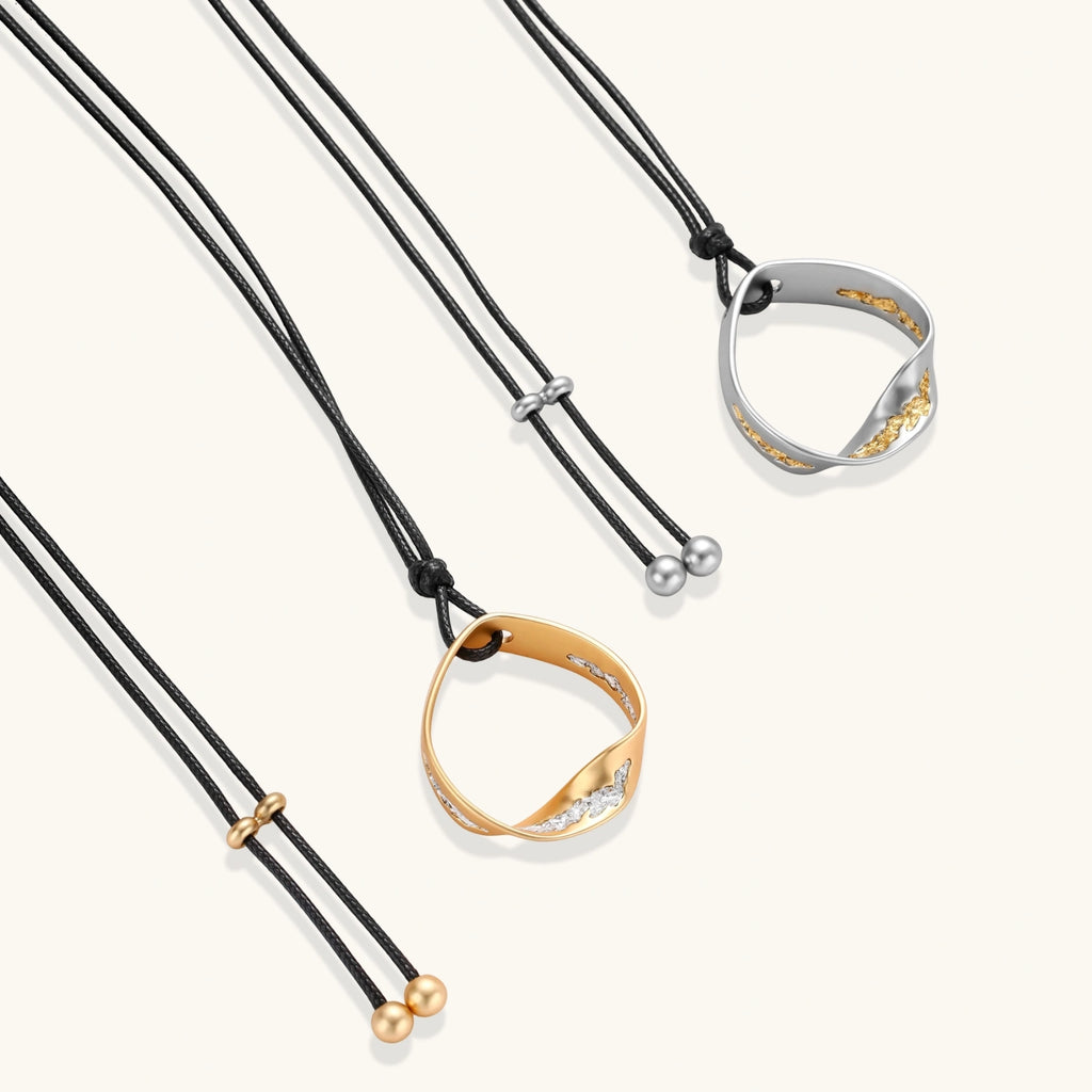 Geometric circle pendant necklace with crystal cluster on adjustable black cord, available in gold and silver finishes.