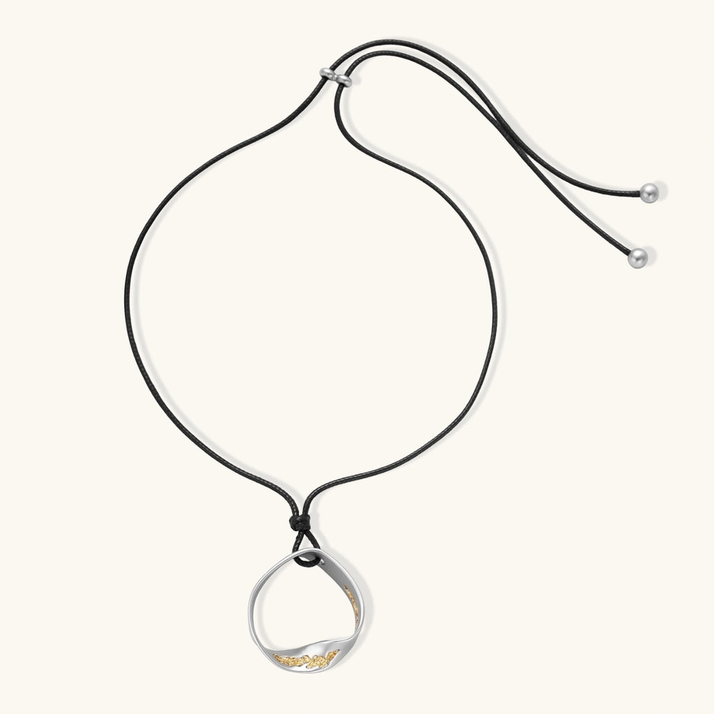 Geometric circle pendant necklace with crystal cluster on adjustable black cord, available in gold and silver finishes.