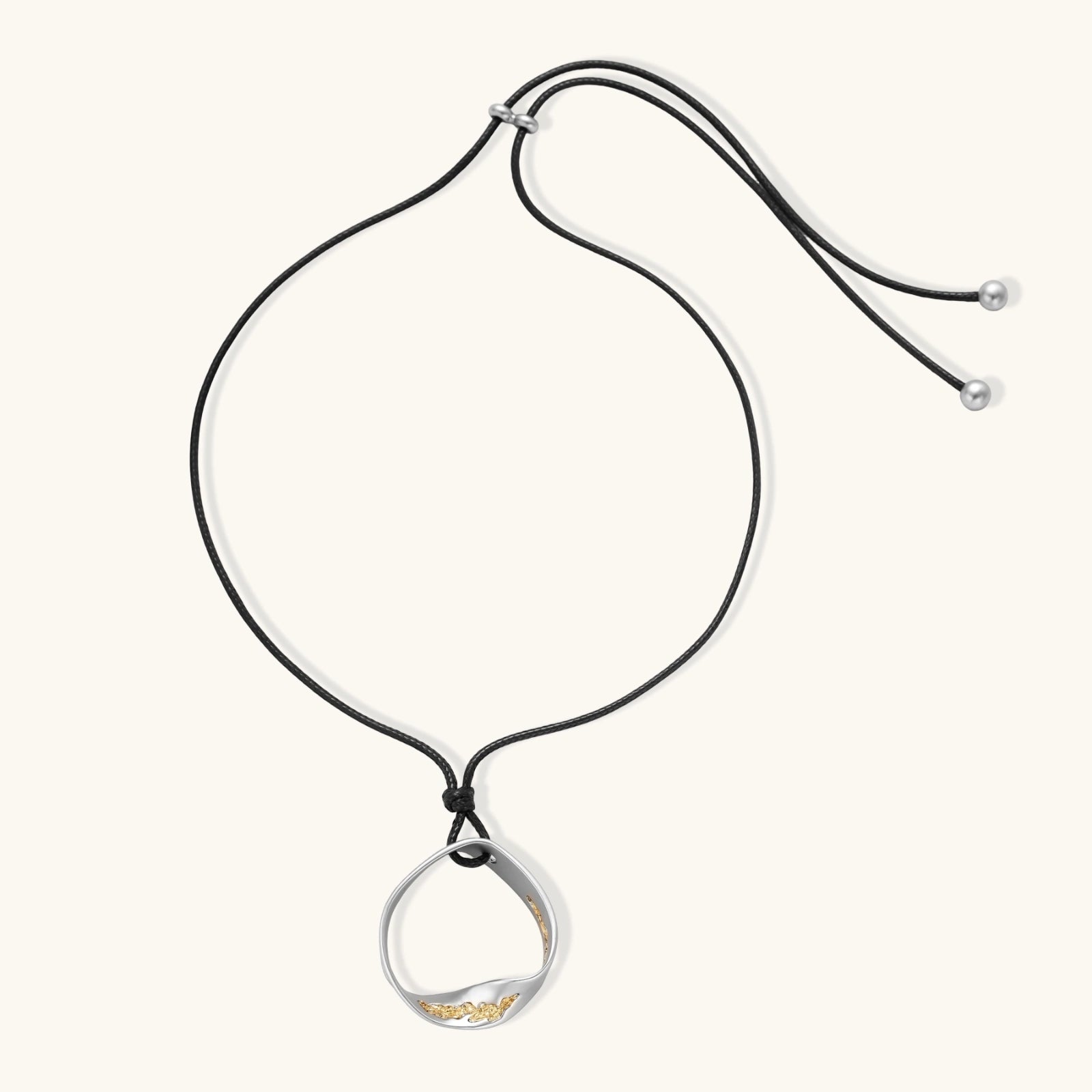 Geometric circle pendant necklace with crystal cluster on adjustable black cord, available in gold and silver finishes.